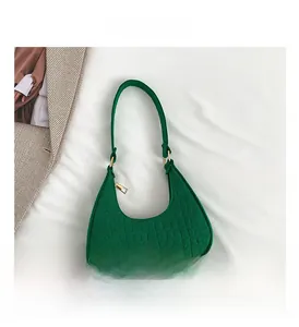 Close-up of green crocodile texture on a crescent shoulder bag with golden hardware