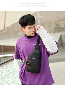 Detail of black crossbody chest bag with earphone port and fashion label on modern strap