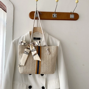 Detail of hand-woven straw tote with cotton rope handles and decorative silk scarf