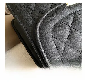 Macro view of black quilted leather with fine stitching and light gold metal hardware