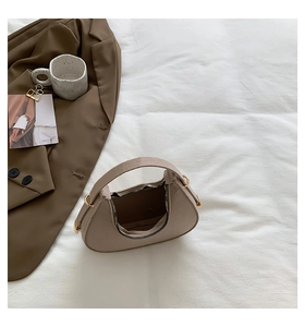 Dettaglio borsa a mezzaluna beige con trama pelle litchi e hardware in metallo dorato