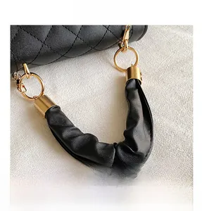 Detail of gold metal ring and lobster clasp on black quilted leather handbag strap