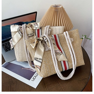 Detail of colorful striped straw tote bag with cotton rope handles and silk scarf detail