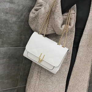 Detail of white quilted chain bag with gold U-shaped buckle and metal shoulder strap