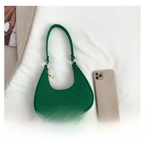Detail of green crocodile textured hobo bag shown with a smartphone for size reference