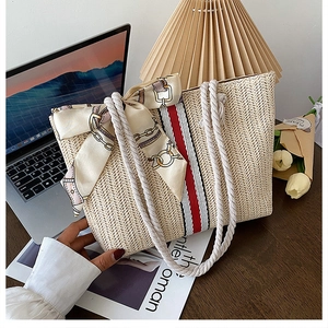 Detail of handwoven straw tote bag featuring red and white stripes and cotton rope handles