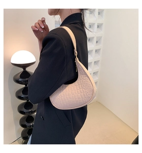 Borsa sottobraccio beige in ecopelle con trama a coccodrillo indossata da una modella