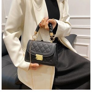 Close-up of black quilted shoulder bag with gold metal buckle and pleated handle detail