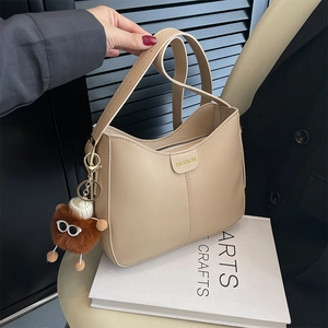 Borsa a secchiello beige minimalista con cerniera e ciondolo di peluche sui libri