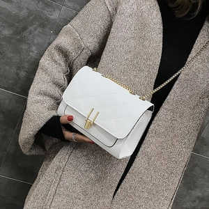 Detail of white quilted crossbody bag featuring a gold rectangular clasp and chain strap