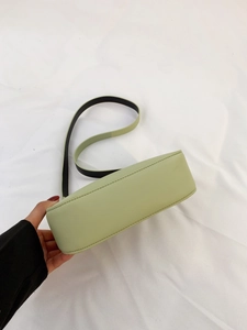 Dettaglio della borsa verde salvia con tracolla a contrasto e trama in pelle liscia