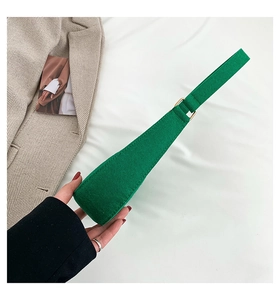 Detailed side view of green felt baguette bag with stone texture and gold metal buckle
