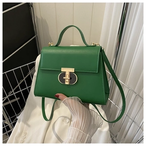 Dettaglio borsa in pelle verde smeraldo con chiusura a T dorata e manico rigido
