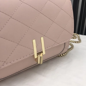 Close-up of light pink quilted leather bag with golden metallic lock and chain strap