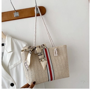 Close-up of beige straw tote bag featuring red stripes and white cotton rope handles