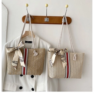 Detail of colorful striped straw tote bag with cotton rope handle and decorative silk scarf