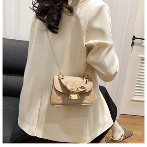 Detailed macro of the beige quilted crossbody bag with gold chain and pleated handle