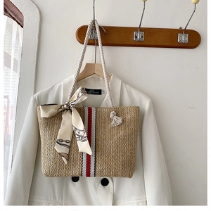 Detail of woven straw tote bag featuring red and white ribbon and soft cotton rope handle
