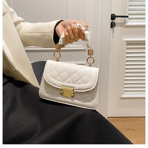 Detailed view of white quilted faux leather handbag with golden twist lock and pleated handle