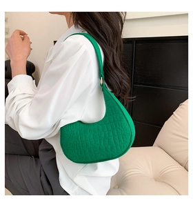 Detail of green faux crocodile texture hobo bag with gold buckle on shoulder