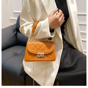 Detail of bright orange quilted leather bag with gold metal clasp and chain strap