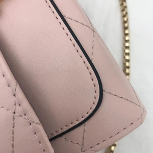 Close-up of pink quilted leather shoulder bag with gold chain and black edge finish