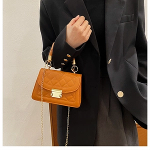 Detail of orange quilted rhombic handbag with gold metal clasp and leather strap
