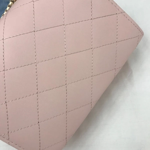 Macro shot of light pink quilted leather bag with elegant stitching and golden zipper detail