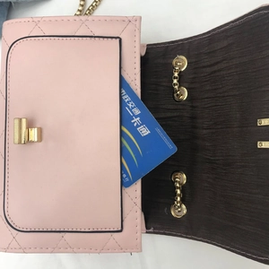 Close-up of pink quilted chain bag with gold rotating lock and interior card pocket