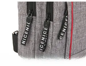 Detail of gray fabric chest bag with black metal zippers and branded ribbon pullers
