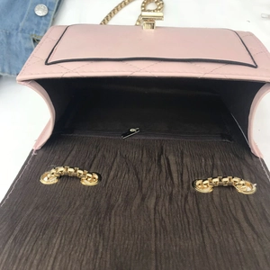 Detailed view of the pink quilted chain bag with gold metal lock and inner zipper pocket