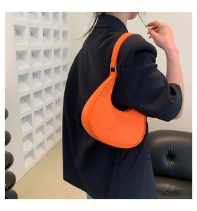 Vibrant orange crocodile pattern hobo bag worn by a model in a black blazer suit
