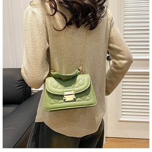 Close-up of a grass green quilted leather crossbody bag with golden chain strap on a model