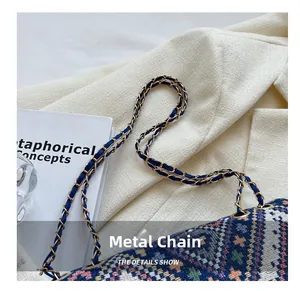 Close-up of woven shoulder bag showing hardware metal chain details on a white blazer