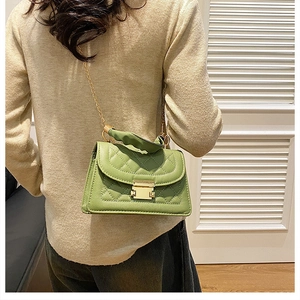 Rear view of model wearing a green quilted handbag with golden chain and clasp
