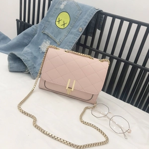 Detail of pink quilted crossbody bag with gold clasp and leather-woven chain strap