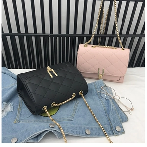 Close-up of quilted chain bags in black and pink with golden T-shaped metal twist locks