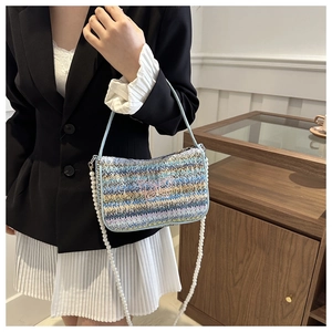 Détail du sac tissé carré avec bordure en cuir bleu et broderie papillon délicate