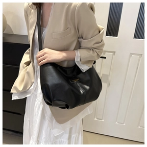 Détail du sac cabas en cuir noir souple montrant la texture douce et la plaque dorée
