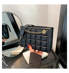 Détail du sac à bandoulière en cuir noir matelassé avec chaîne dorée décorative