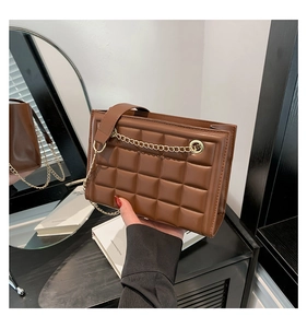 Détail du sac bandoulière marron matelassé avec chaîne dorée et texture raffinée