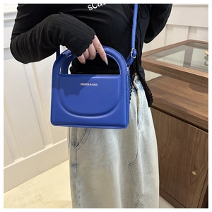Detailed view of the vibrant blue PU leather handbag with integrated semicircular handle
