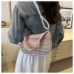 Detail of colorful woven crossbody bag featuring butterfly embroidery and pearl strap