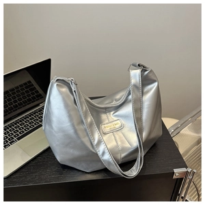 Détail du sac à bandoulière argenté métallisé montrant la texture lisse et l'étiquette