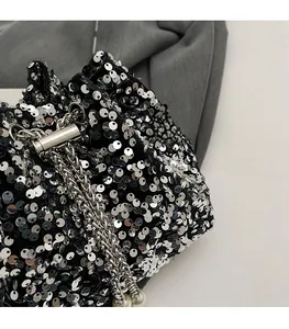 Dettagli di paillettes argento su velluto nero con catena e chiusura in metallo
