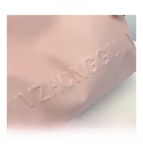 Primer plano del bolso rosa con letras en relieve y textura de material de calidad