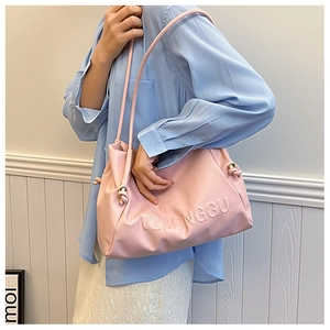 Primer plano de bolso tote de cuero rosa con letras en relieve llevado por una modelo