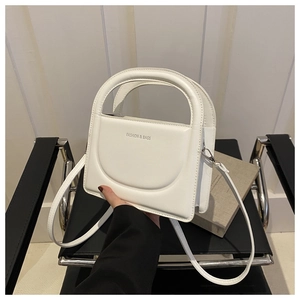 Close-up of white leather small square bag with circular handle and silver hardware