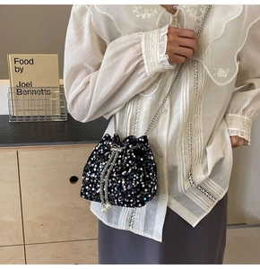 Détail du sac seau noir à paillettes avec chaîne argentée et perles blanches décoratives