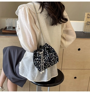 Détail d'un sac seau noir à paillettes avec bandoulière chaîne et ornements en perles